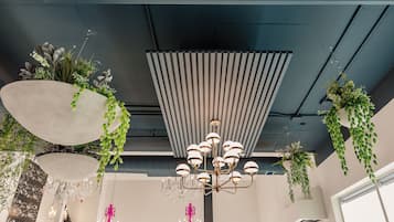 A modern interior with hanging planters, a chandelier, and a ceiling with exposed beams.
