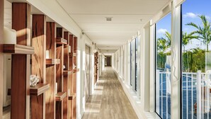 A hotel corridor with wooden paneling, large windows, and a view of a pool area. - Kompose Boutique Hotel (Sarasota)