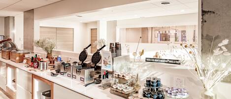 A buffet area with various food items, a coffee station, and a sign promoting a monthly vacation offer.