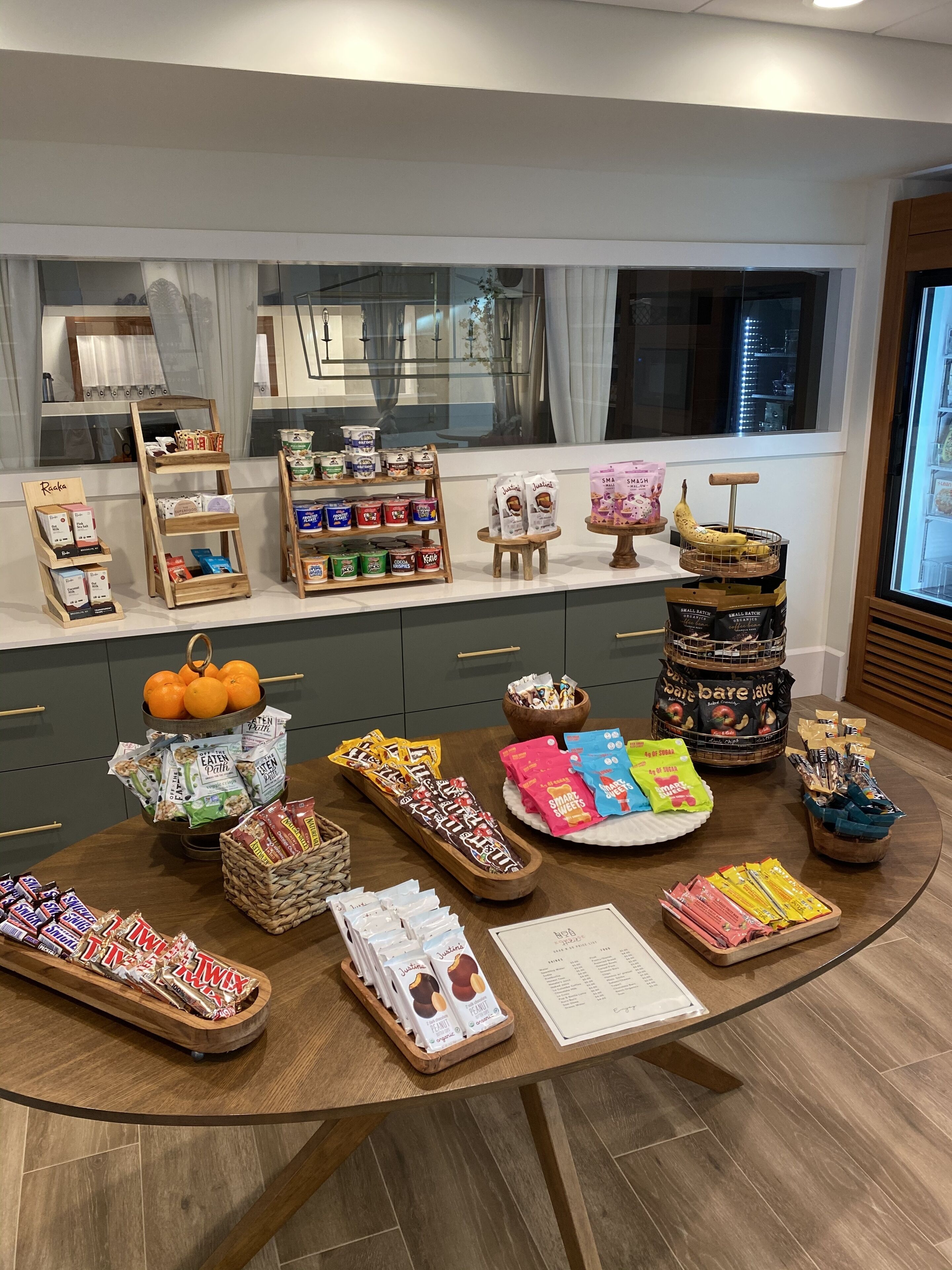 A well-organized display of snacks and beverages in a modern setting with wooden furniture and a view of the city through large windows.