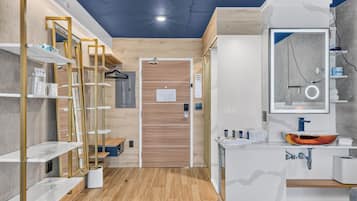 A modern bathroom with a wooden door, a mirror with a circular frame, and a sink with a unique basin design.
