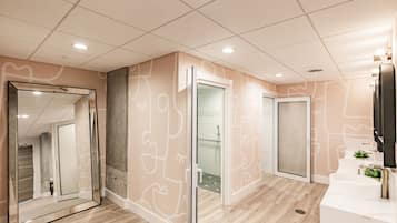 A modern bathroom with a large mirror, a shower area, and a reception desk.