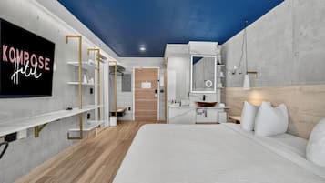 A modern hotel room with a bed, a TV, a desk, and a wardrobe.