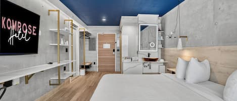 A modern hotel room with a bed, a TV, a desk, and a wardrobe.