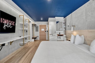 Una habitación de hotel moderna con una cama, televisión, escritorio y armario.