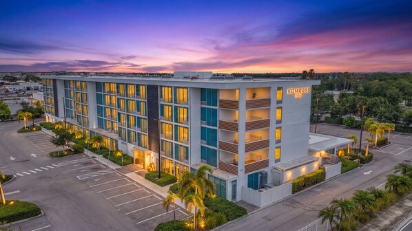 A multi-story hotel with a modern design, featuring a parking lot and landscaped areas. - Kompose Boutique Hotel (Sarasota)