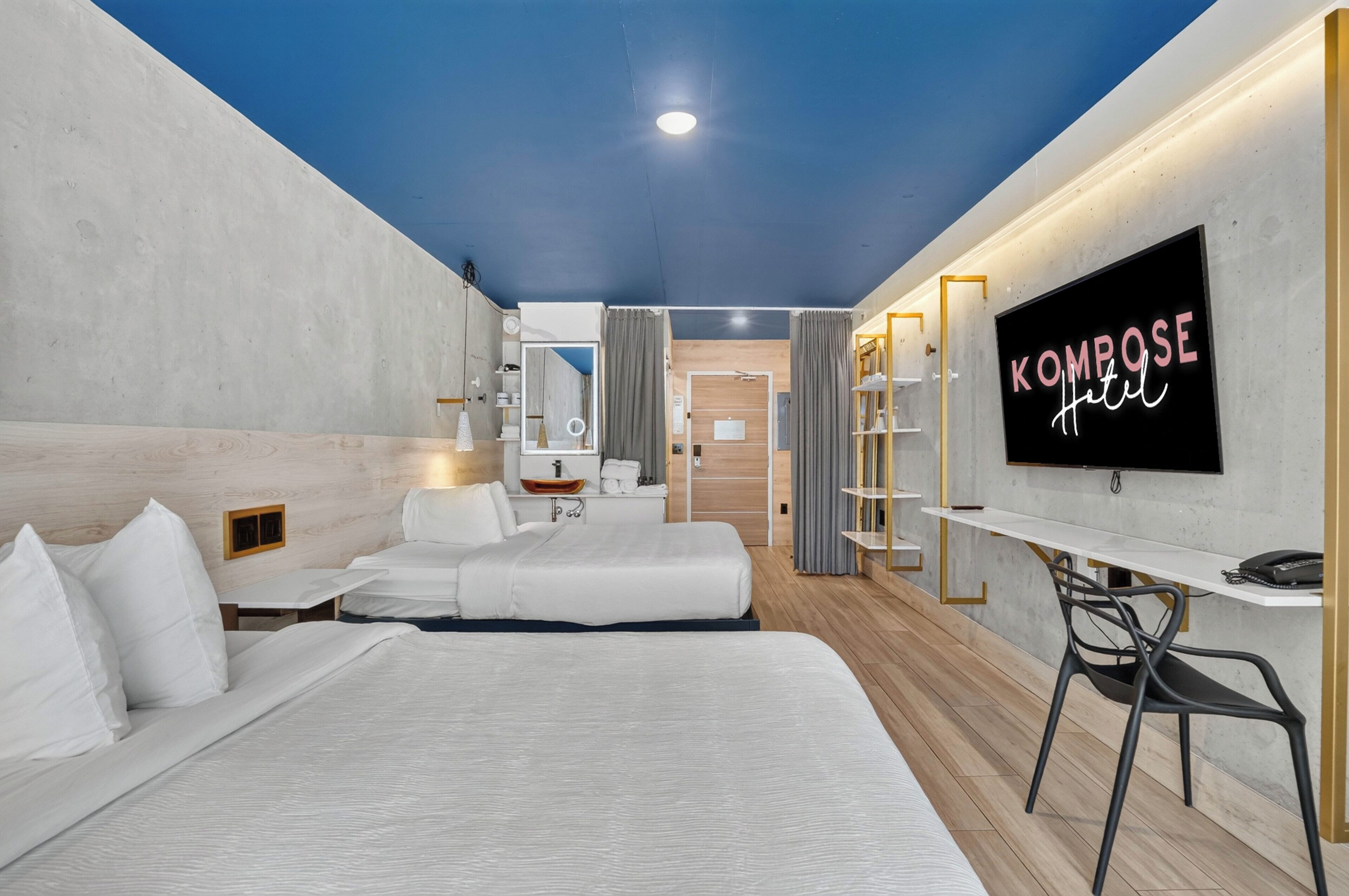 Una habitación de hotel con cama, escritorio, televisor y espejo.