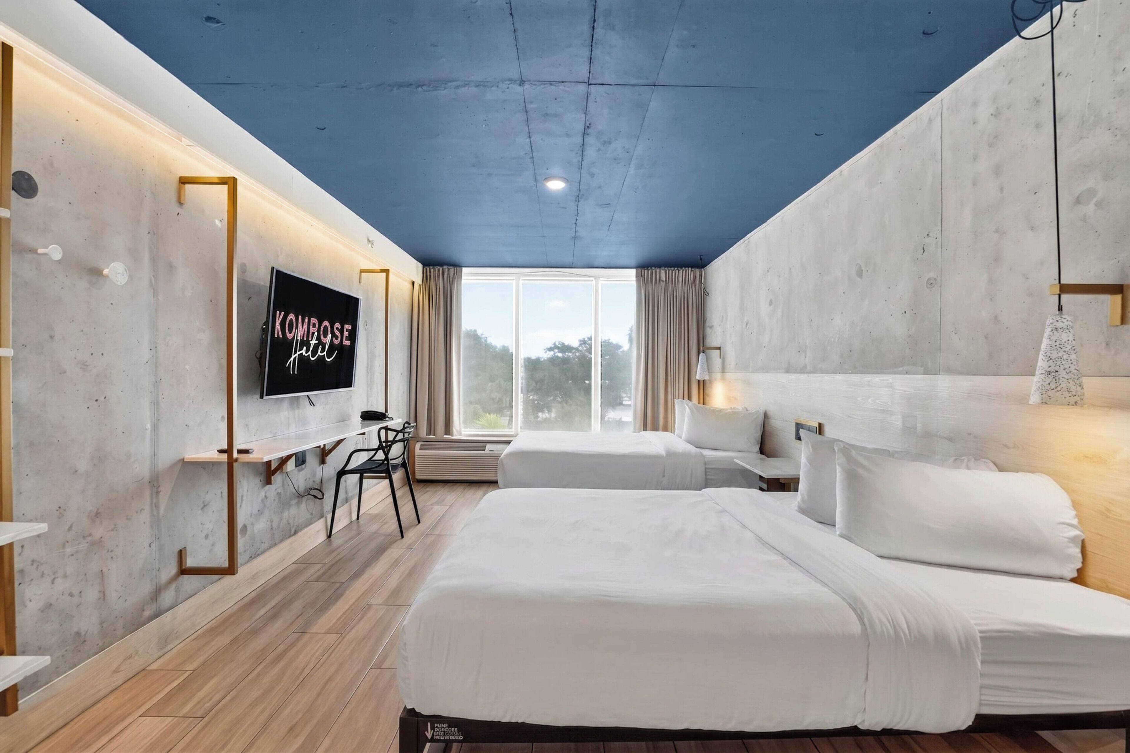 Une chambre d’hôtel moderne avec un grand lit, un bureau et un téléviseur fixé au mur.