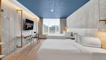 Une chambre d’hôtel moderne avec un grand lit, un bureau et un téléviseur fixé au mur.