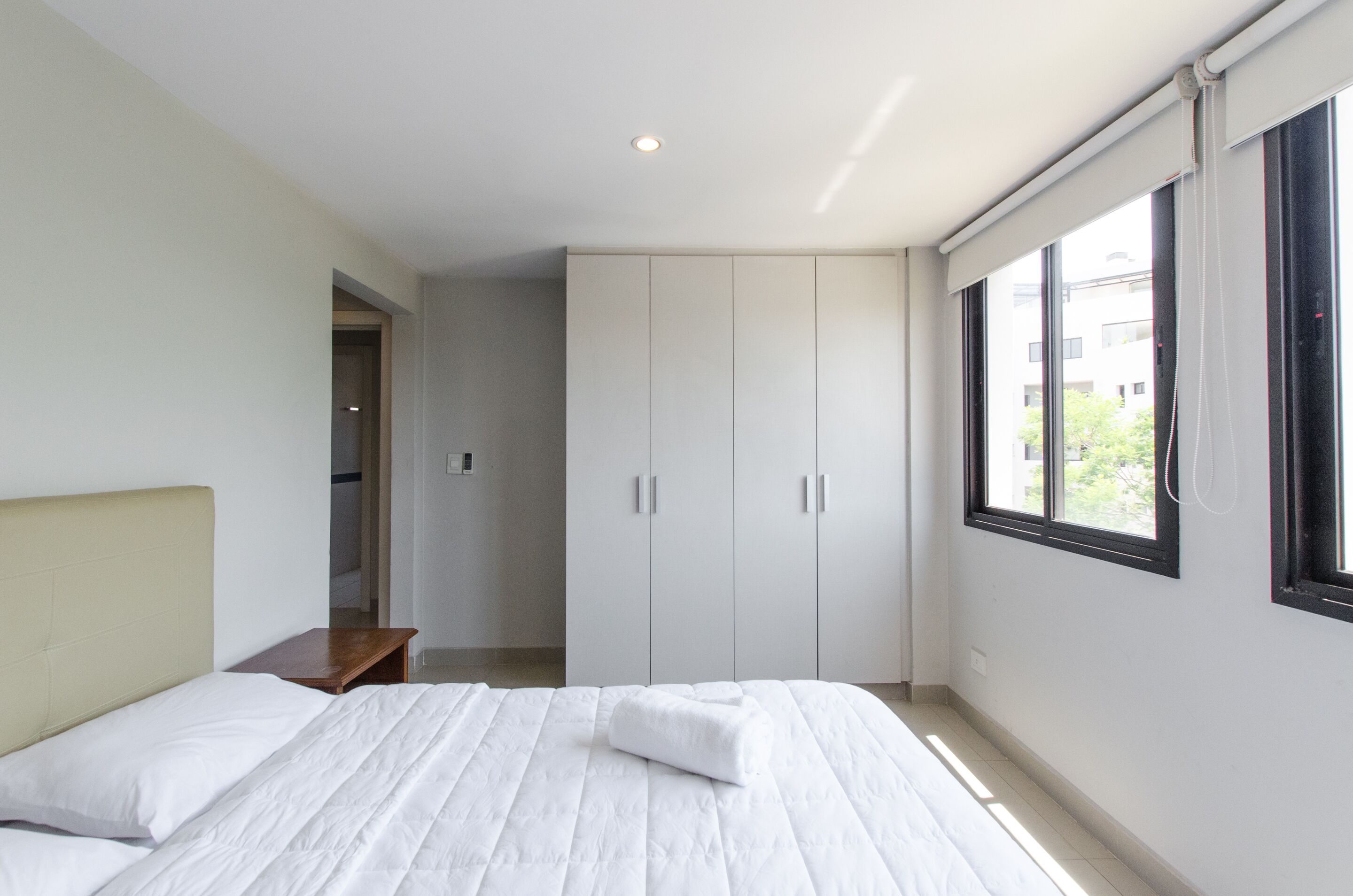 A bedroom with a bed, a wardrobe, a window, and a door.