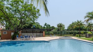 A swimming pool with lounge chairs and a covered seating area.