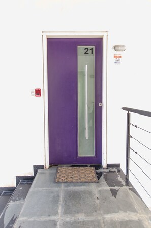 A purple door with the number 21, a fire alarm, and a doormat. - Flats Presidente (Asunción)