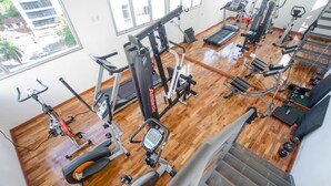 Een sportschool met diverse fitnessapparaten, een loopband en gewichten.