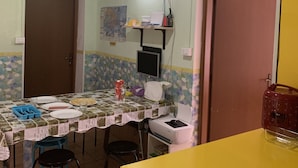Une petite cuisine bien éclairée, avec une table à manger, des chaises et un comptoir jaune.
