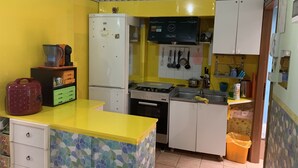 Une cuisine de taille réduite avec un plan de travail jaune, des armoires blanches et un pare-feu décoré de motifs.