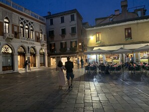A historic square with cobblestone pavement, a theater, and outdoor seating areas with umbrellas. - Pavarotti House (Venice)