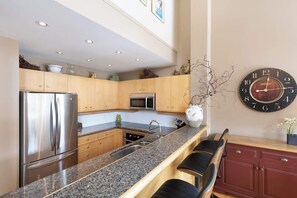 Una cocina moderna con encimeras de granito, electrodomésticos de acero inoxidable y armarios de madera.