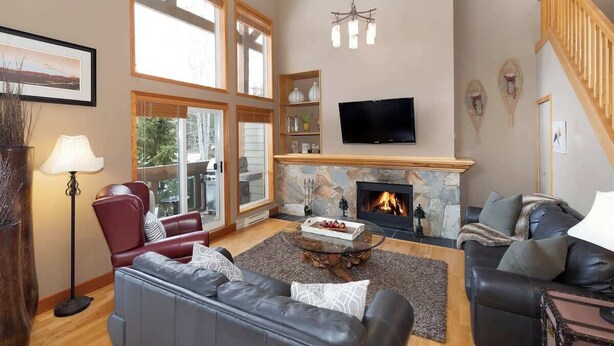 A spacious living room with a fireplace, leather sofas, a television, and large windows. - Overlooking Golf Course & Valley Trail, Parking (Whistler)