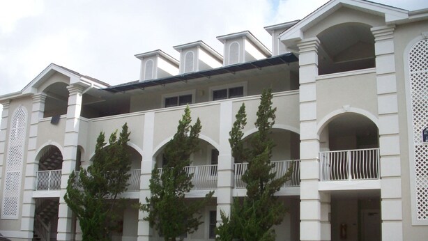 A multi-story building with a symmetrical facade, featuring balconies and large windows. - 202 Colony II (Sunset Beach)