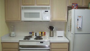 A kitchen with a microwave, stove, toaster, and refrigerator. - 202 Colony II (Sunset Beach)