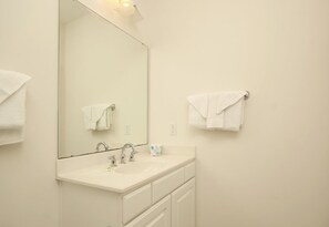 A bathroom with a large mirror, a sink, and two towel racks. - 1302 Crow Creek Drive (Calabash)