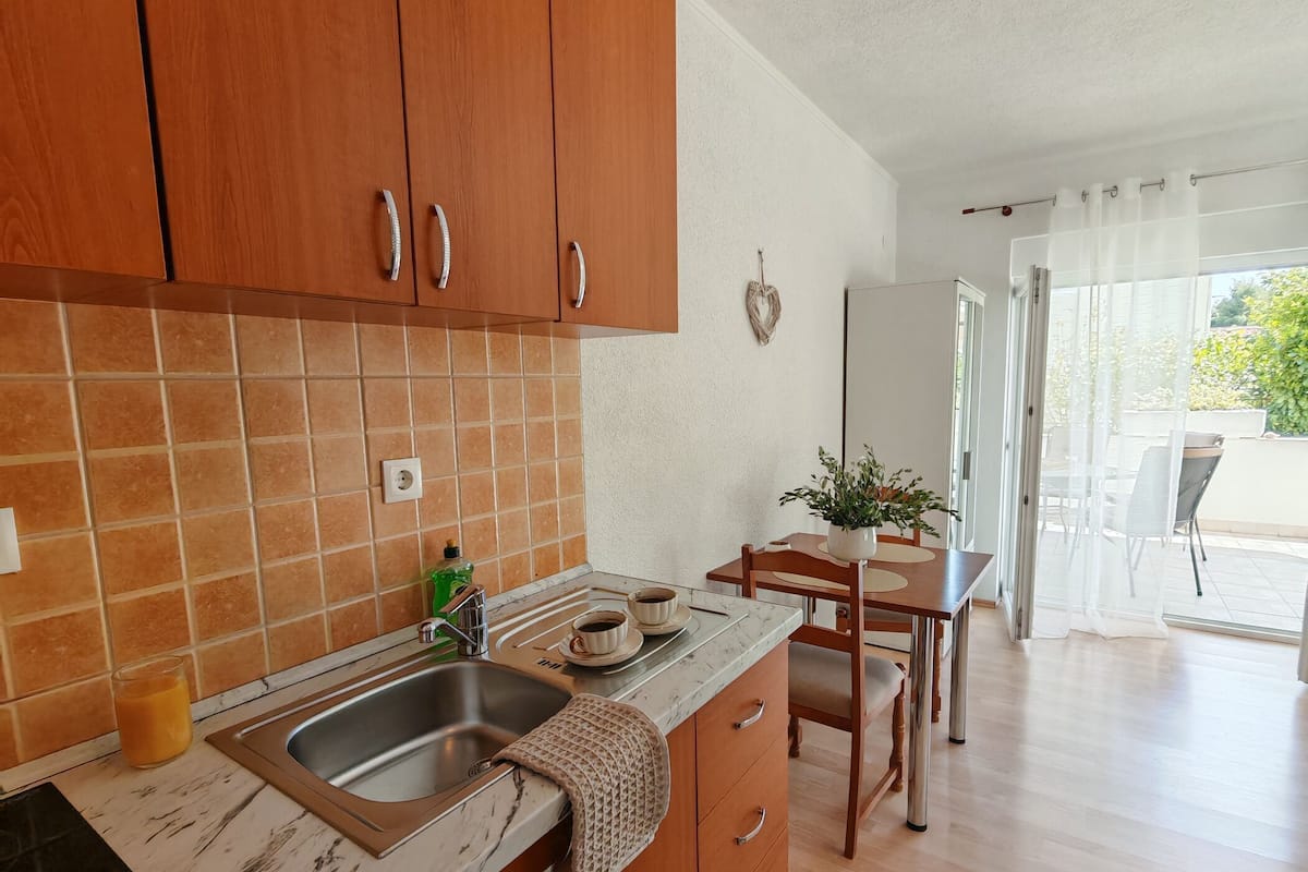 Une cuisine avec des meubles de rangement en bois, un évier et un coin repas comprenant une table et des chaises.