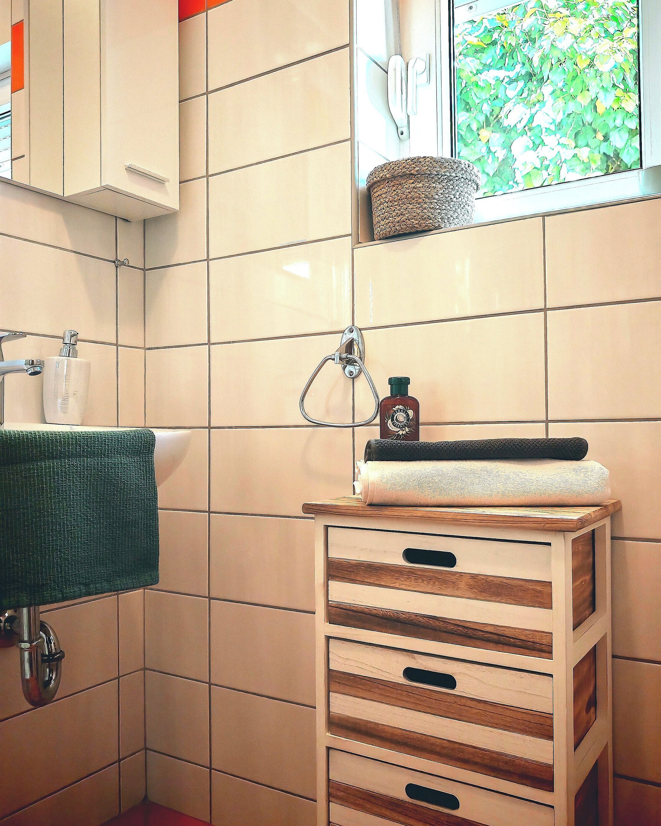 A bathroom with a sink, towel, and a window with a view of greenery.