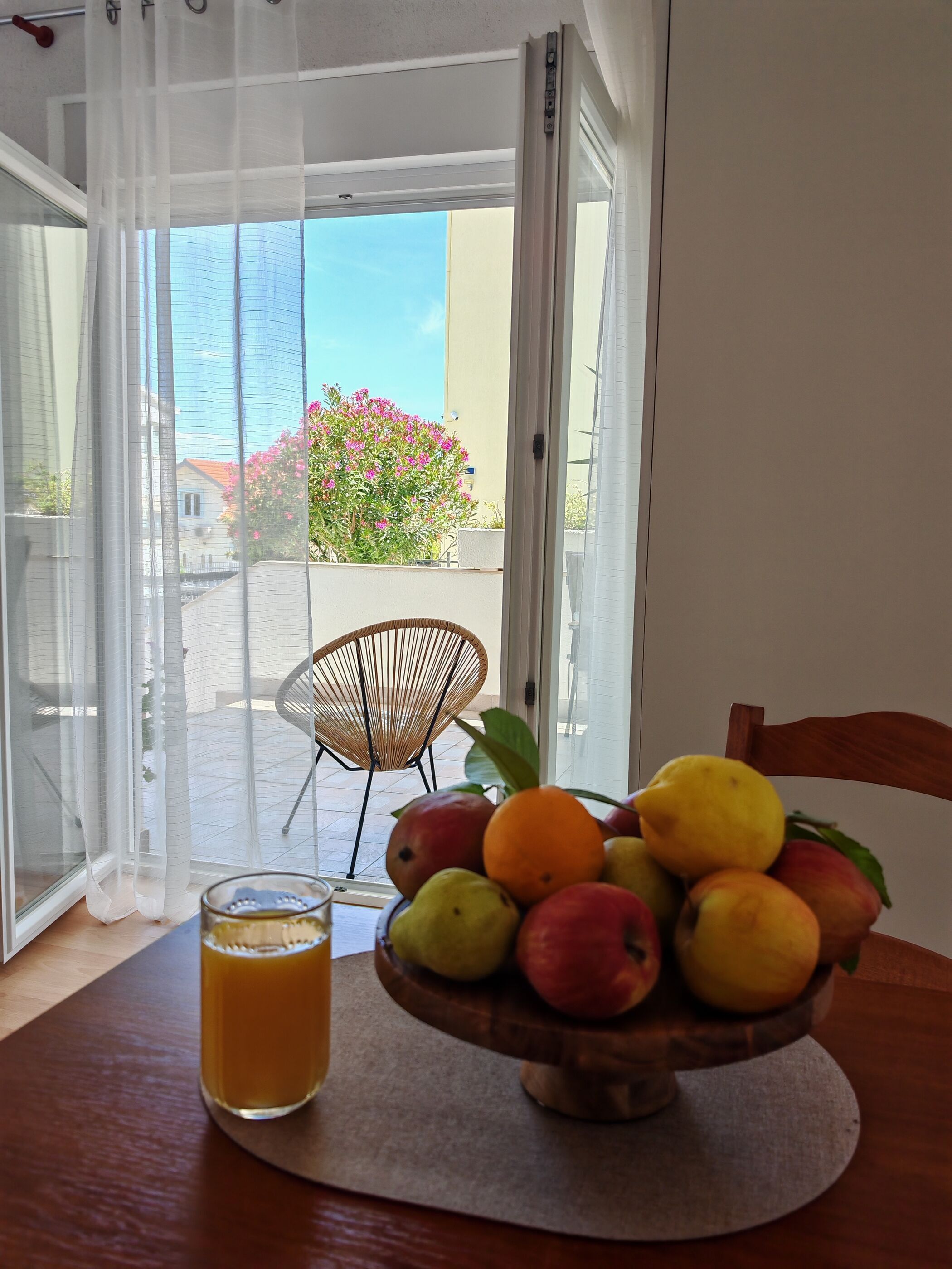 Ein Essbereich mit Tisch, Obstschale und einem Glas Saft.
