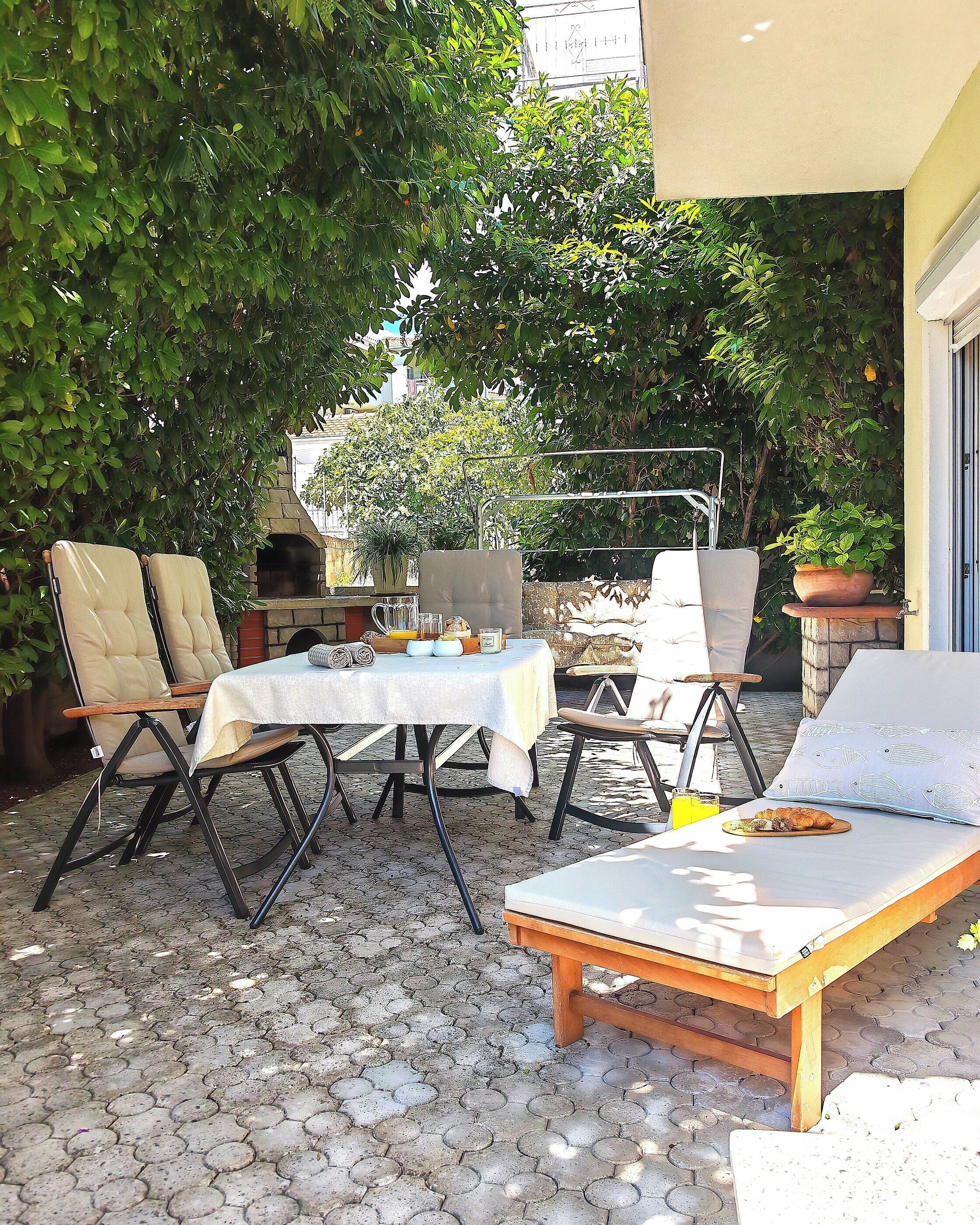 Een terras buiten met een tafel, stoelen en een lounge fauteuil.
