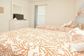 A bedroom with a bed, a dresser, a television, and a window with blinds.