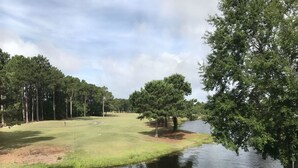 Un campo da golf con specchio d'acqua e alberi.