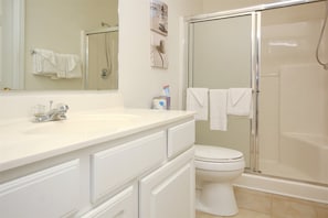 A bathroom with a white sink, a toilet, and a glass-enclosed shower.