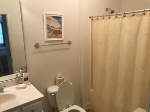 A bathroom with a toilet, sink, and shower curtain. - 2311 Crow Creek (Calabash)