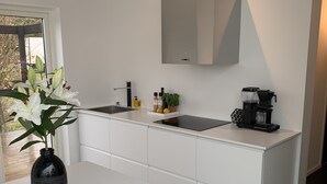 A modern kitchen with white cabinetry, a black coffee maker, and a vase with flowers on the counter. - Modern house with stunning ocean view and heated private pool (30°) (Borgholm N)