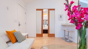 Ein modernes Wohnzimmer mit einer Couch, einem Glastisch und einer farbenfrohen Blumenkomposition.