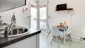 A modern kitchen with a sink, a dining table with chairs, and a television mounted above the table. - Maison Port En Dro by Interhome (Carnac)
