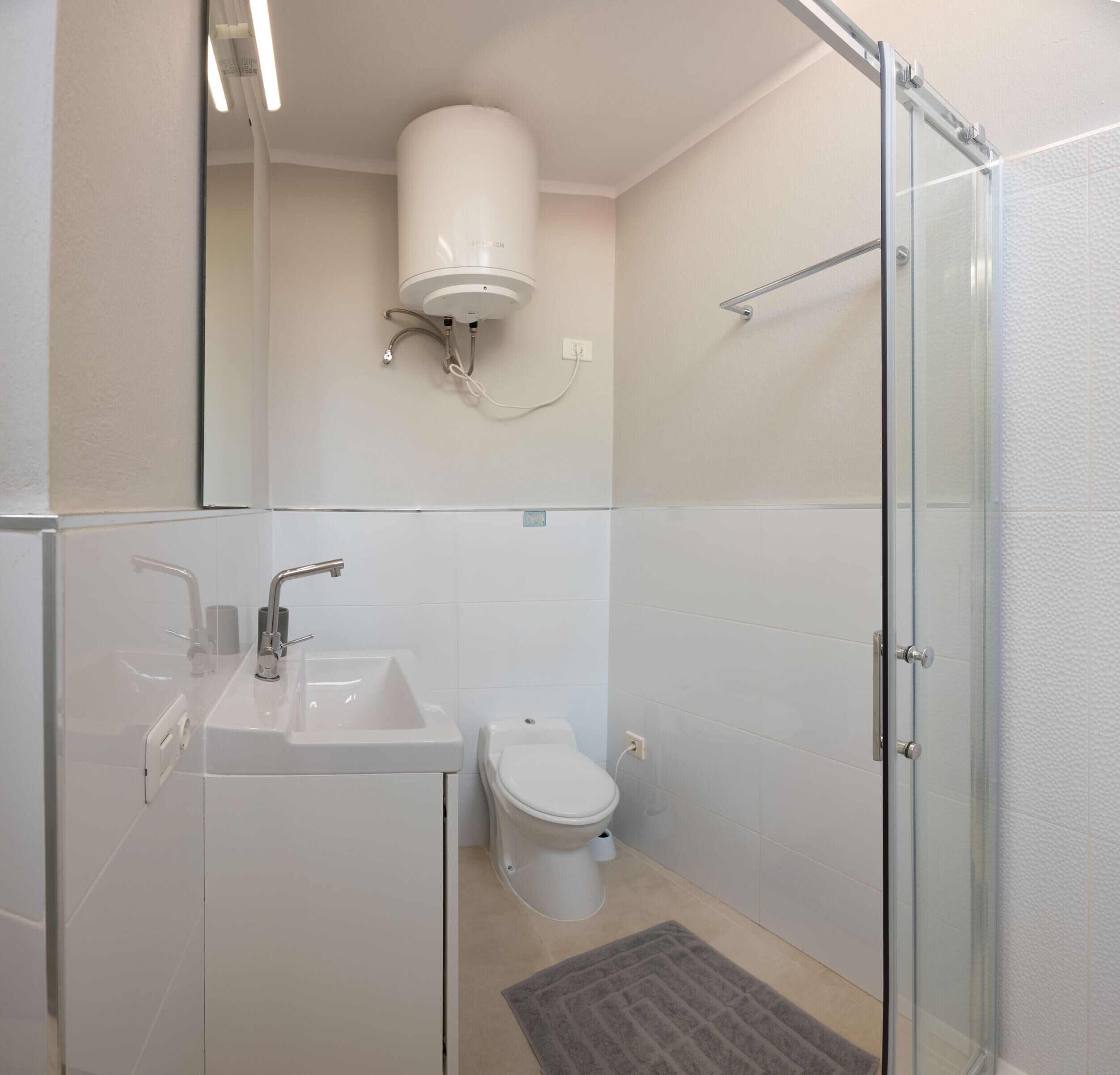 A bathroom with a glass shower enclosure, a sink, and a toilet.