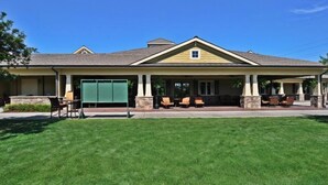 A two-story building with a covered patio area, stone pillars, and outdoor seating. - 1202 Crow Creek Drive (Calabash)