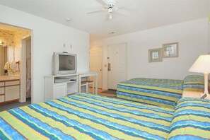 A hotel room with two beds, a television on a stand, a desk, and a door. - 201 River Creek Sea Trail (Sunset Beach)