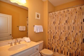 A bathroom with a sink, mirror, toilet, and shower curtain. - 1402 Crow Creek Drive (Calabash)