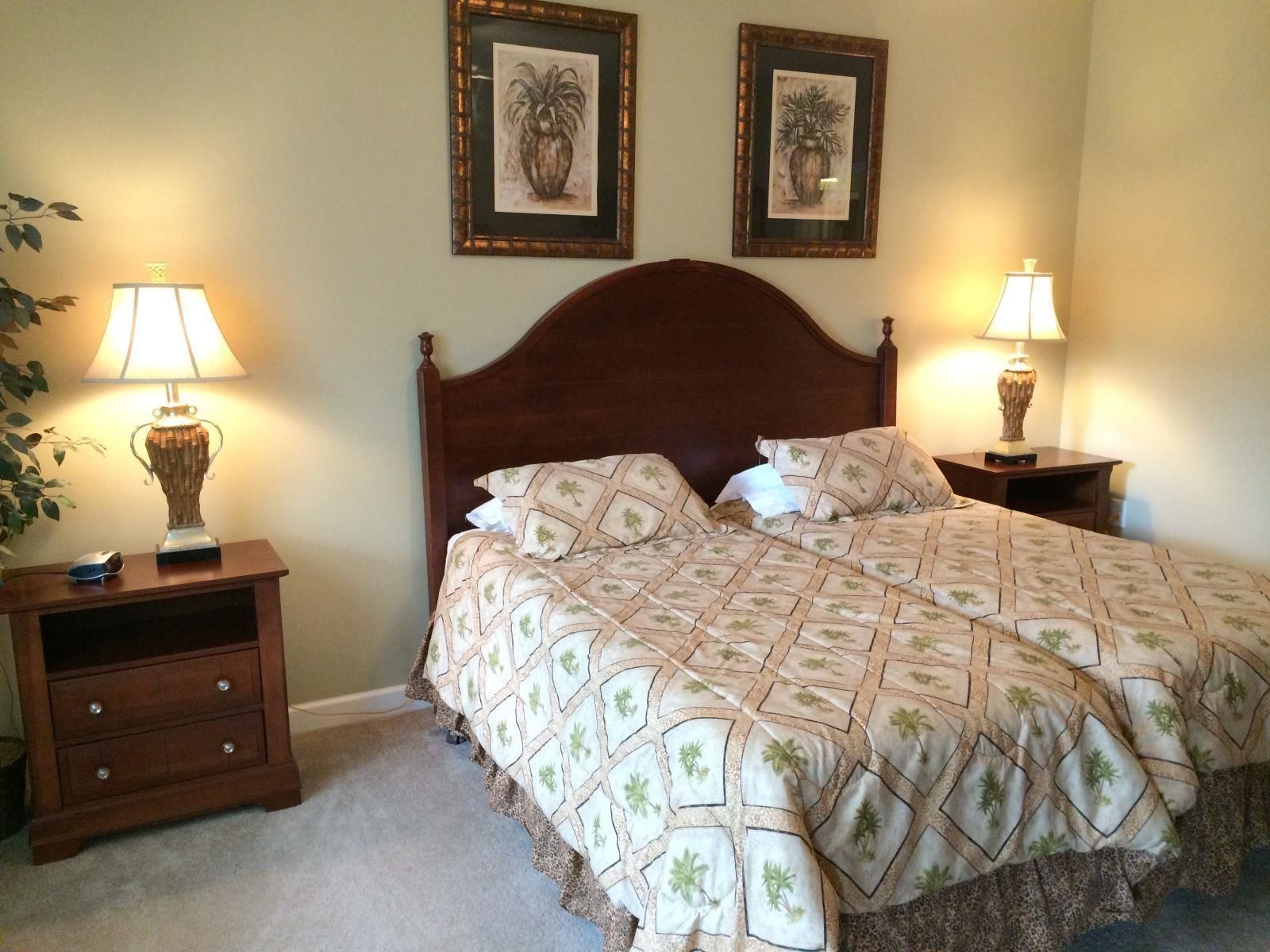 Un dormitorio con una cama grande, dos mesitas de noche, un aparador y dos lámparas de pared.