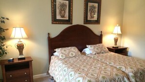 Un dormitorio con una cama grande, dos mesitas de noche, un aparador y dos lámparas de pared.