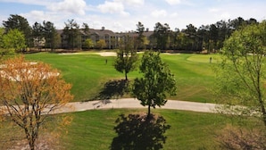 Un campo da golf con un percorso ben definito, alberi e un edificio sullo sfondo.