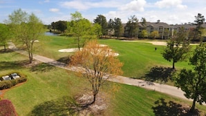 Un campo da golf con un percorso ben definito, alberi e un edificio sullo sfondo.