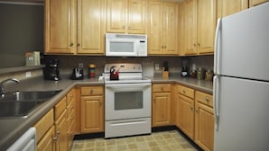 Una cucina con mobili in legno, un forno a microonde bianco, un fornello e un frigorifero.