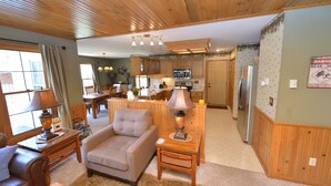A cozy living room with a sofa, a table with a lamp, and a dining area with a table and chairs.