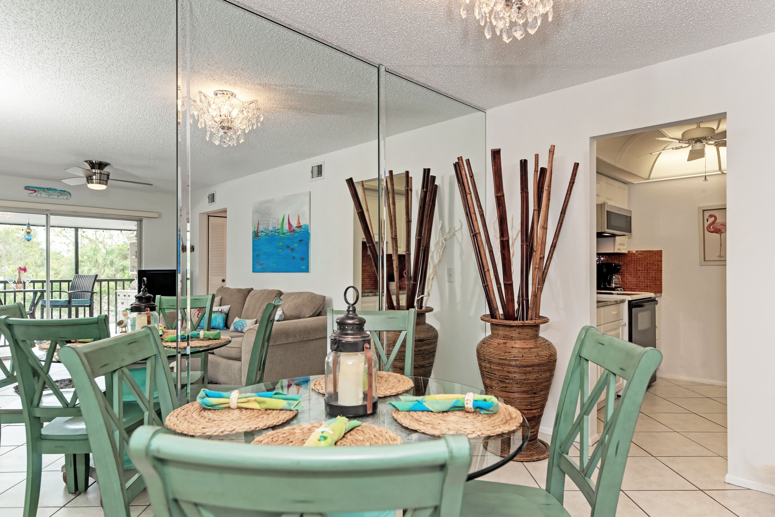 A dining area with a glass table, green chairs, and a decorative vase with sticks.