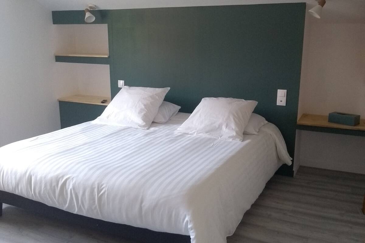 A bed with white bedding, a wooden headboard, and a nightstand with a lamp.