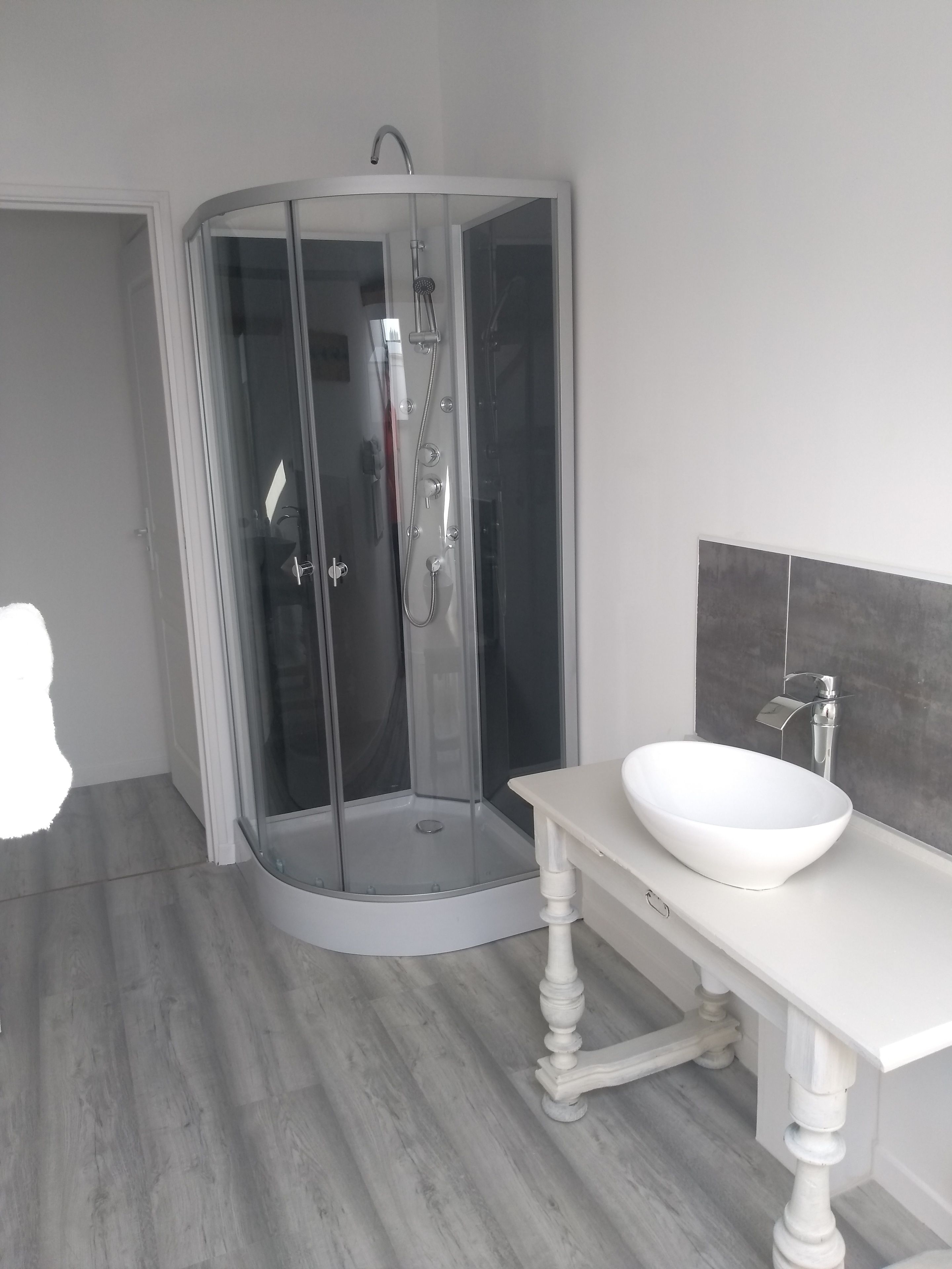 A modern bathroom with a glass-enclosed shower, a white sink, and a wooden vanity.