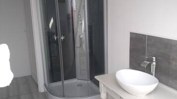 A modern bathroom with a glass-enclosed shower, a white sink, and a wooden vanity.